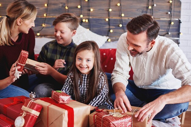 Happy children opening christmas present with parents