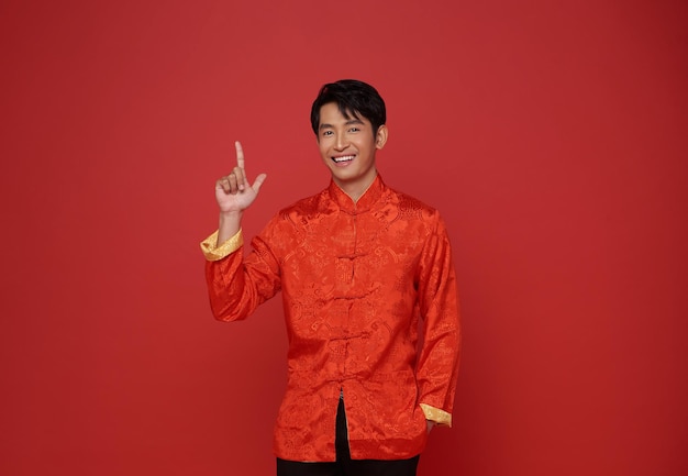 Free photo happy chinese new year 2024 asian man wearing red traditional costume and hands pointing finger up