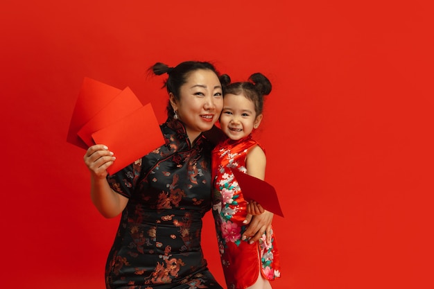 旧正月おめでとう。赤い背景で隔離のアジアの母と娘の肖像画