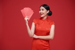 無料写真 幸せな中国の旧正月アジア女性アンパオまたは赤いパケットの金銭的な贈り物と金のインゴットを保持しています。