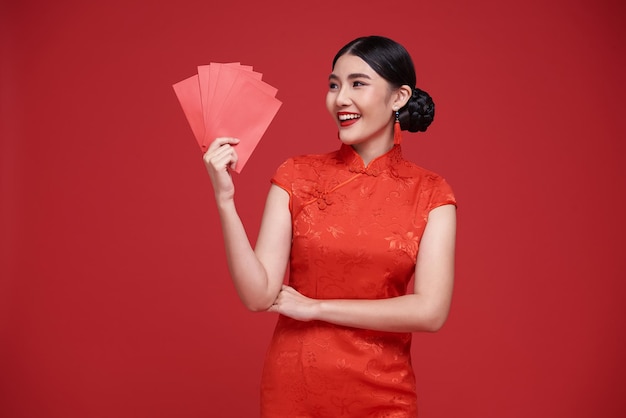С китайским Новым годом азиатка держит ангпао или красный пакет с денежным подарком и золотым слитком