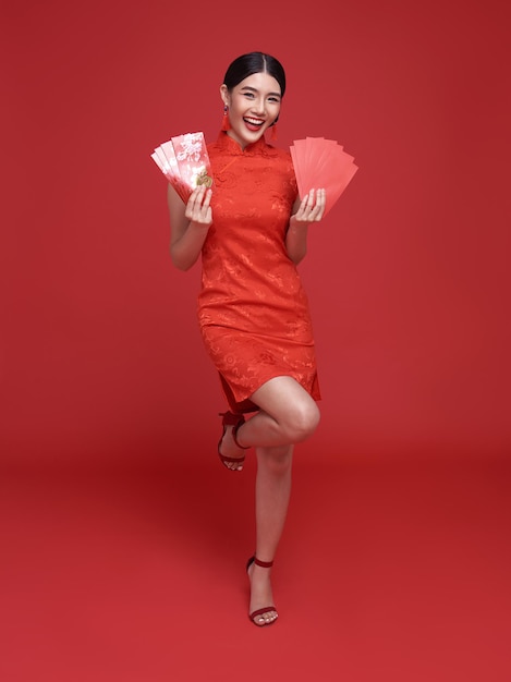 Angpao를 들고 전통적인 치파오 치파오 드레스를 입고 행복 한 중국 새 해 아시아 여자
