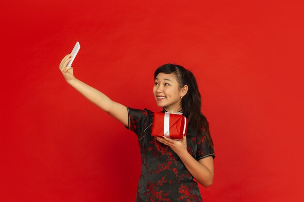 旧正月おめでとう。赤い背景で隔離のアジアの若い女の子の肖像画