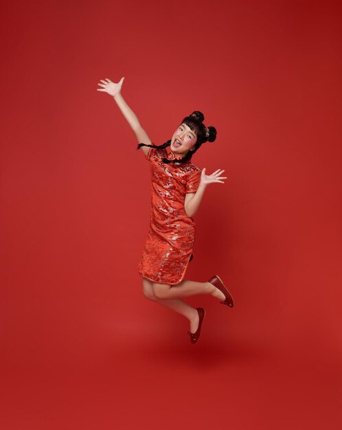 Happy Chinese new year Happy smiling children asian girl wearing traditional qipao dress jumping celebrate isolated on red background