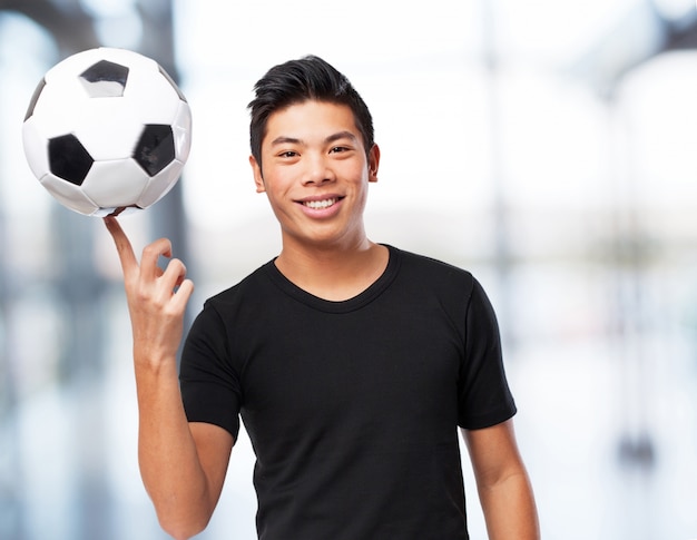 Foto gratuita felice cinese-sport-uomo con il calcio-ball