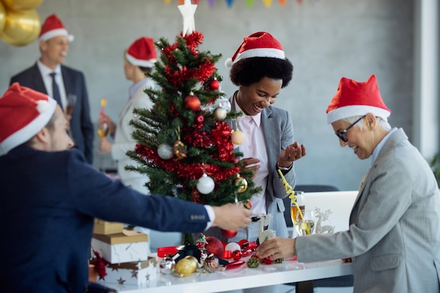 Happy colleagues decorating Christmas tree on a party in the office