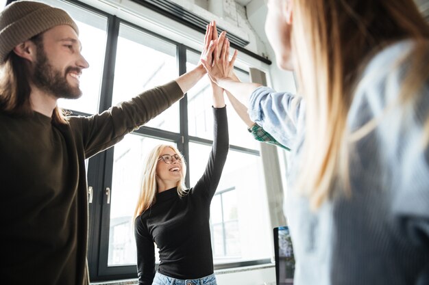 Happy colleagues in office give high five to each other