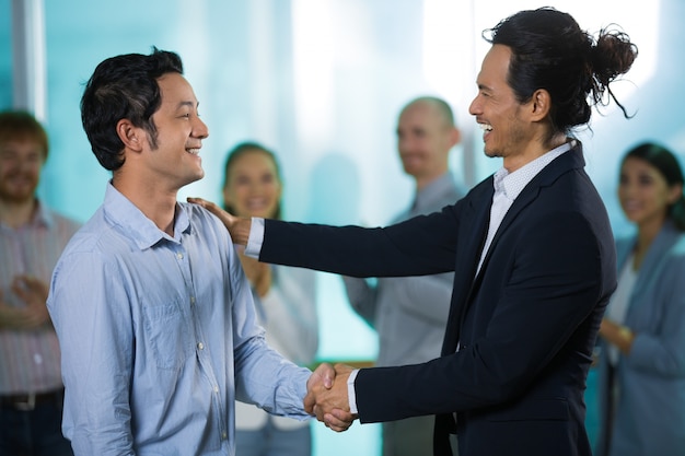 Free photo happy colleagues talking while shaking hands