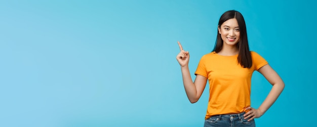 Happy confident asian girl selfassured pointing upper left corner show way smiling determined assert