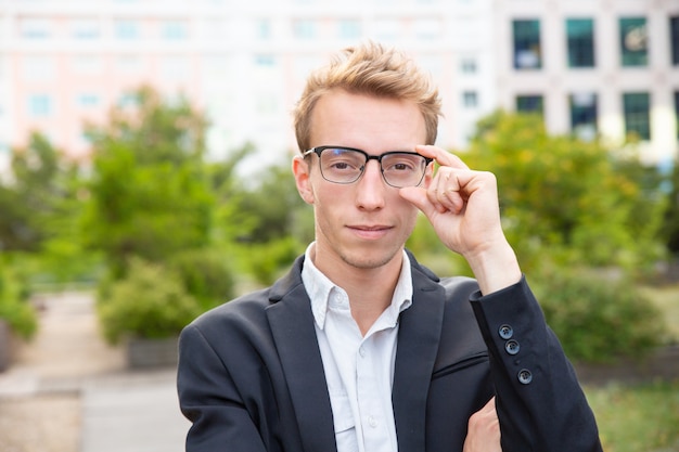 Happy confident businessman in glasses standing for camera