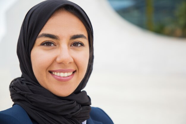 Счастливая уверенно мусульманская бизнес-леди представляя снаружи