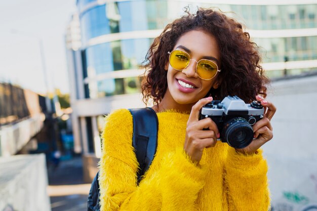 Free photo happy confident  woman holding photo camera and walking in big modern city. w