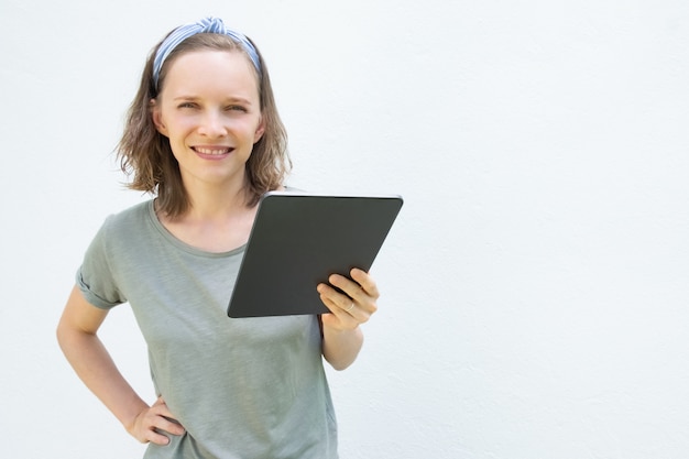 Счастливая уверенно молодая женщина держа цифровое устройство