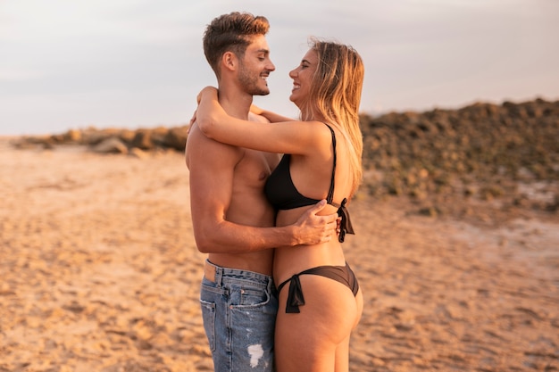 Free photo happy couple at beach hugging