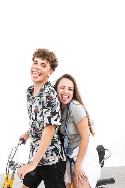 Happy couple on bicycle against white wall teasing