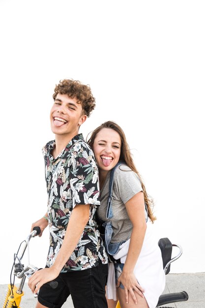 Happy couple on bicycle against white wall teasing