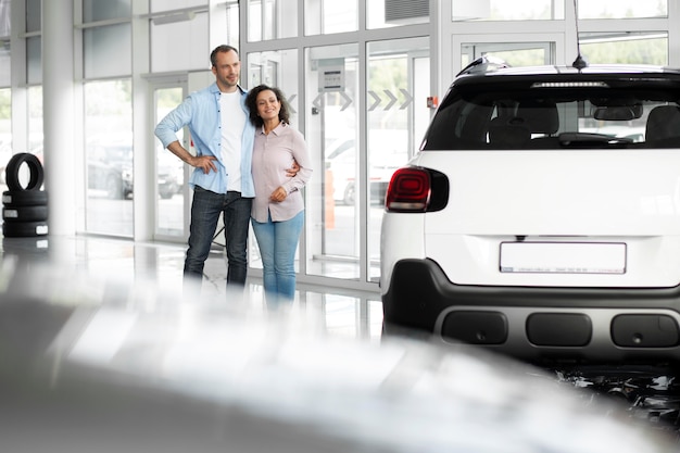 Happy couple in car showroom dealership