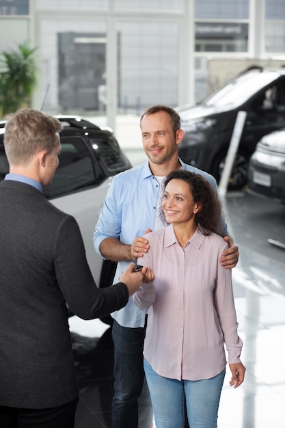 Happy couple in car showroom dealership