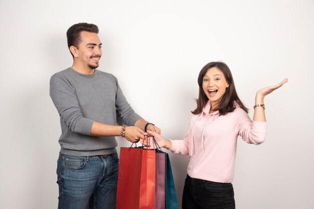 Happy couple carrying shopping bags on white.