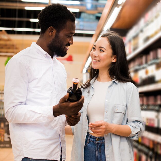 Happy couple choosing wine in grocery store