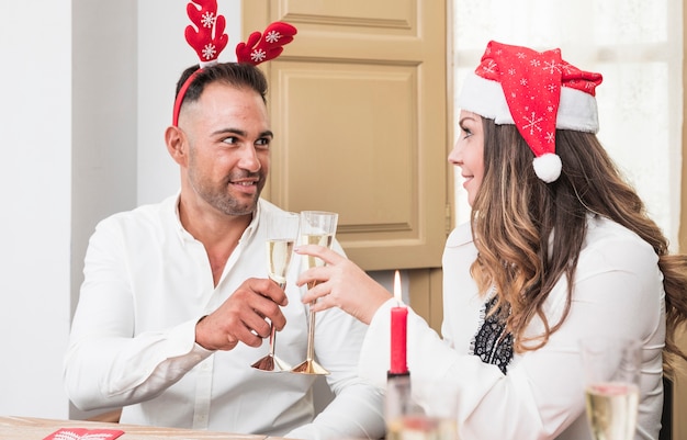 お祝いのテーブルでシャンパンのメガネを握っている幸せな夫婦