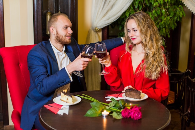 Happy couple clanging glasses at table in restaurant