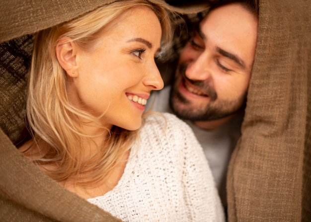 Happy couple covered with blanket closeup