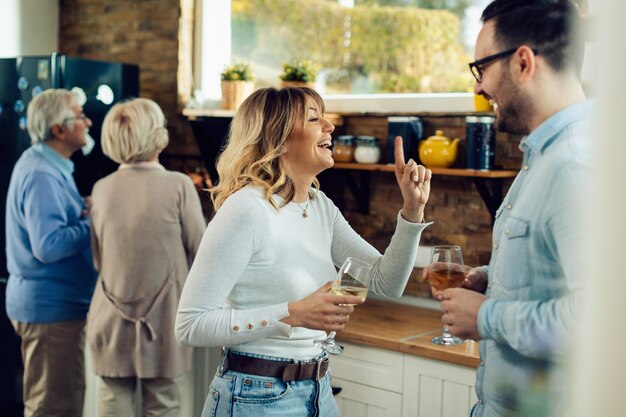 Happy couple drinking wine and communicating in the kitchen Senior couple is preparing food in the background