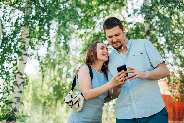 Happy couple in earphones messaging on mobile