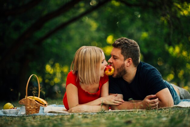 Happy couple eating an apple outside