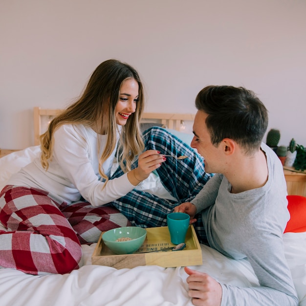 Happy couple eating breakfast in bed