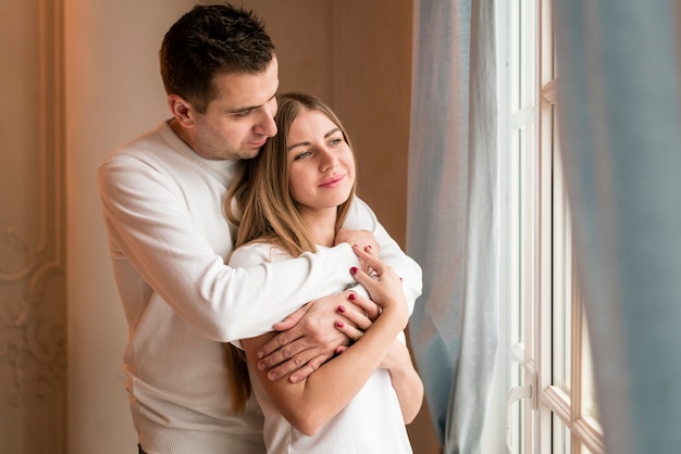 Happy couple embraced and looking through window