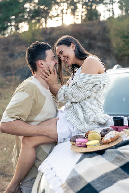 Free photo happy couple enjoy a summer weekend with a car outside the city in a field