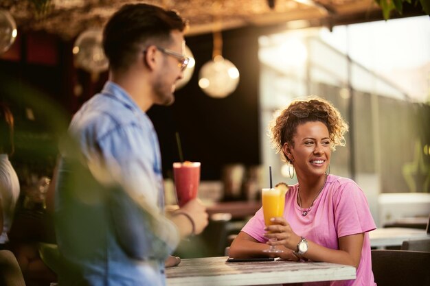 Happy couple enjoying in a bar and drinking cocktails Focus is on woman