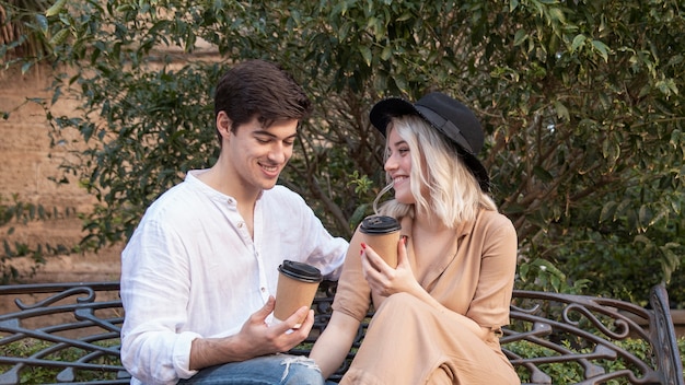happy couple enjoying coffee on the bench