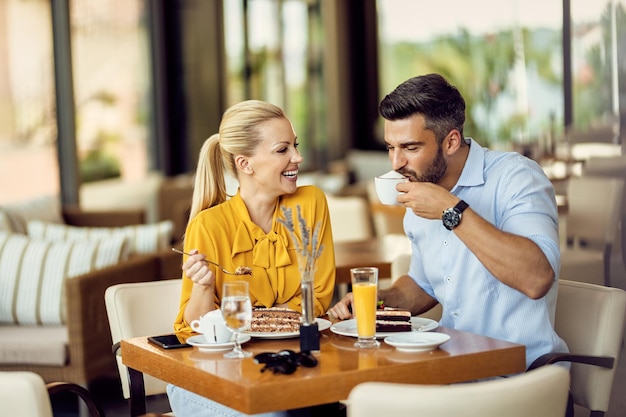 Coppia felice godendo in una tazza di caffè e dessert in un bar