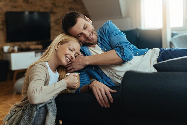 Happy couple enjoying while sitting close to each other and relaxing at home