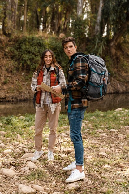 Happy couple in the forest holding a map long shot