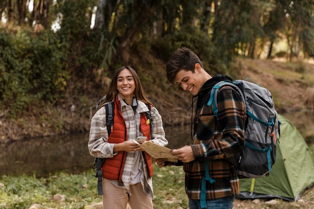 Happy couple in the forest reading a map