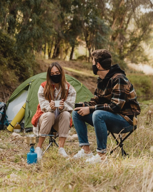 Foto gratuita coppia felice nella foresta indossando maschere mediche