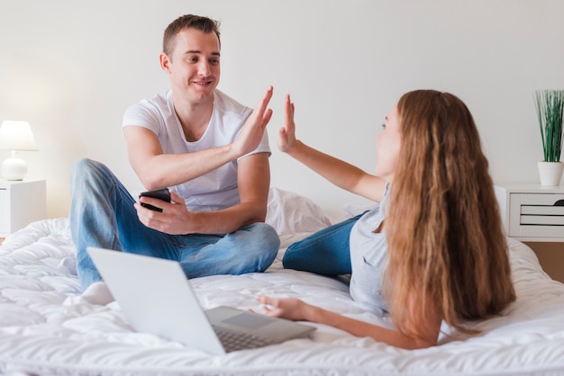 Happy couple giving high five on bed