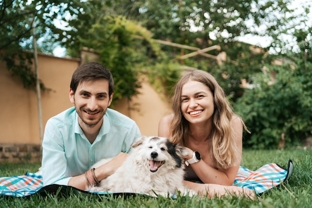 Free photo happy couple of guys playing with their dog in the backyard on the grass. cheerful old dog