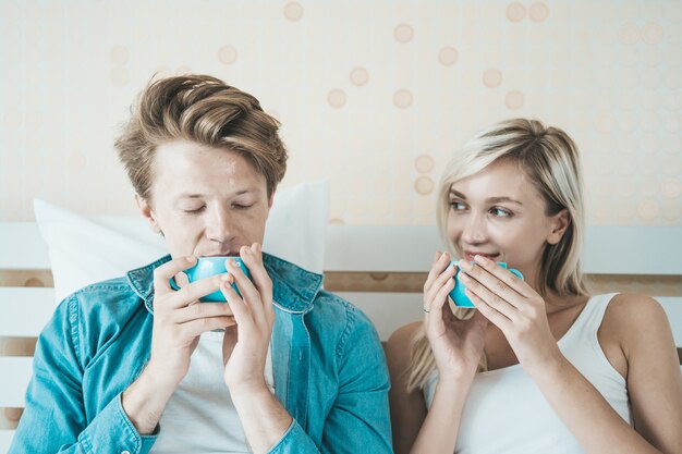 幸せなカップルの手持ち株カップと朝のコーヒーを飲む