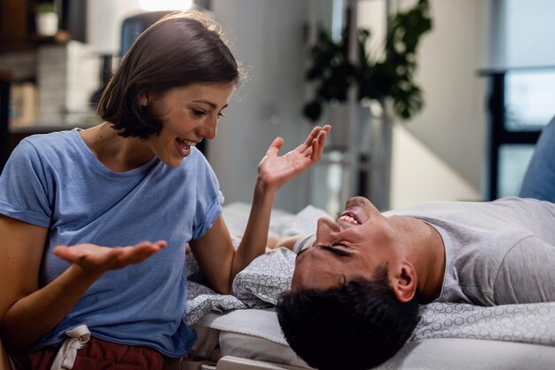 Happy couple having fun and laughing while communicating in the bedroom