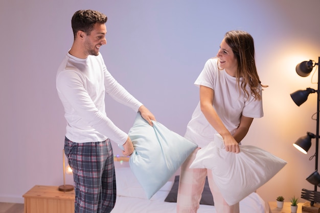 Happy couple having a pillow fight