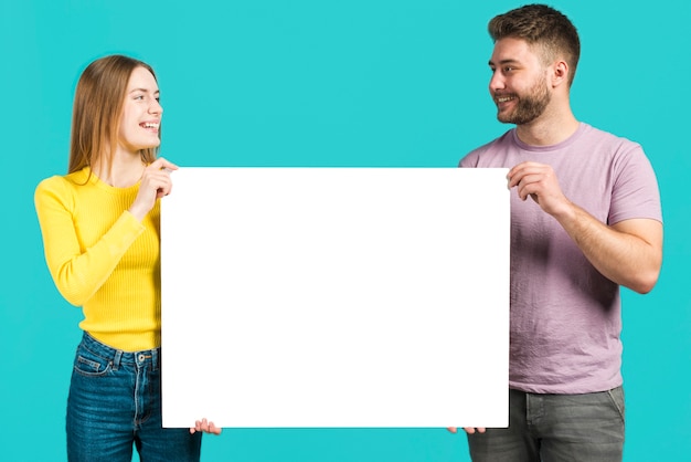 Free photo happy couple holding blank sign