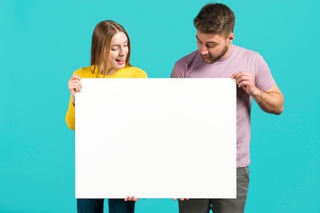 Free photo happy couple holding blank sign