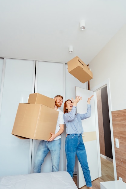Free photo happy couple holding cardboard boxes and moving to new place