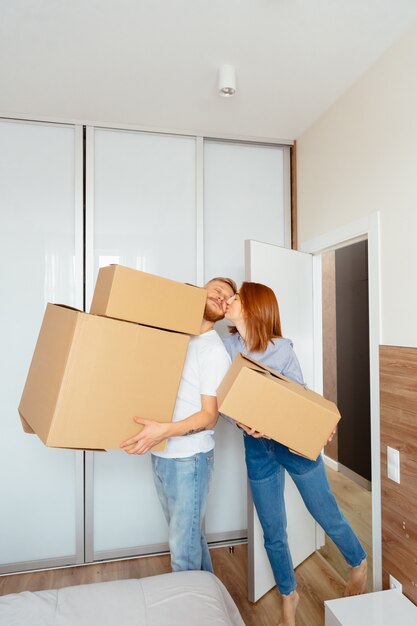 Счастливая пара держит картонные коробки и переезжает на новое место