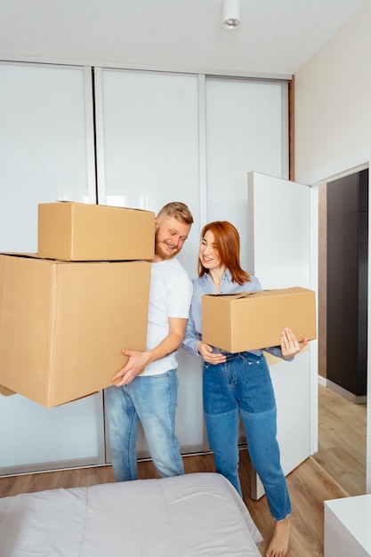 Happy couple holding cardboard boxes and moving to new place